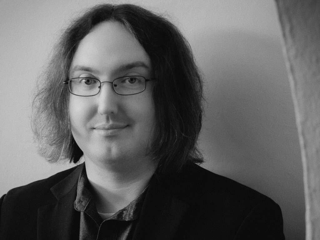Black and white photo of Michael Dodin standing inside a curved archway.